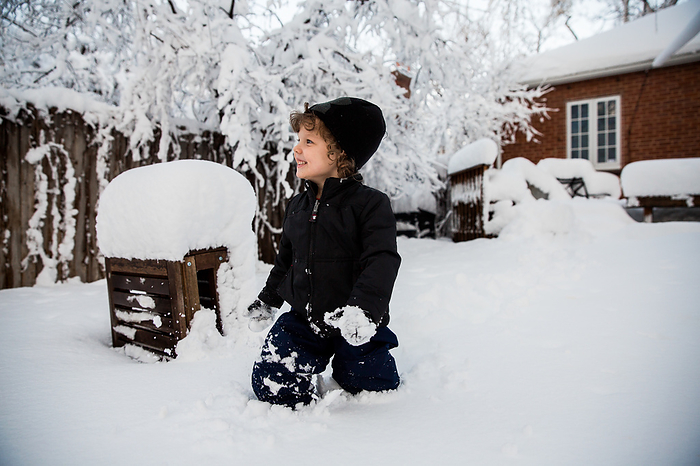 Young boy playing in the snow in backyard