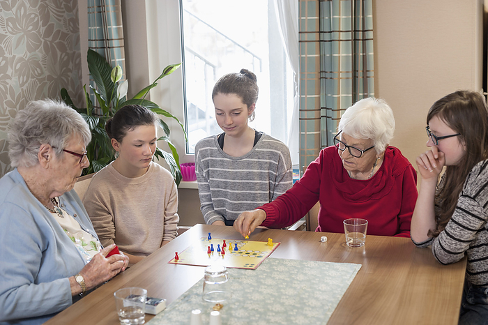Girls playing board game with senior women in rest home Girls playing ludo board game with senior women in rest home