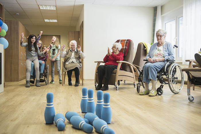 scholar girls playing bowling with seniors in rest home, special care home, nursing home Girls playing bowling with senior women in rest home