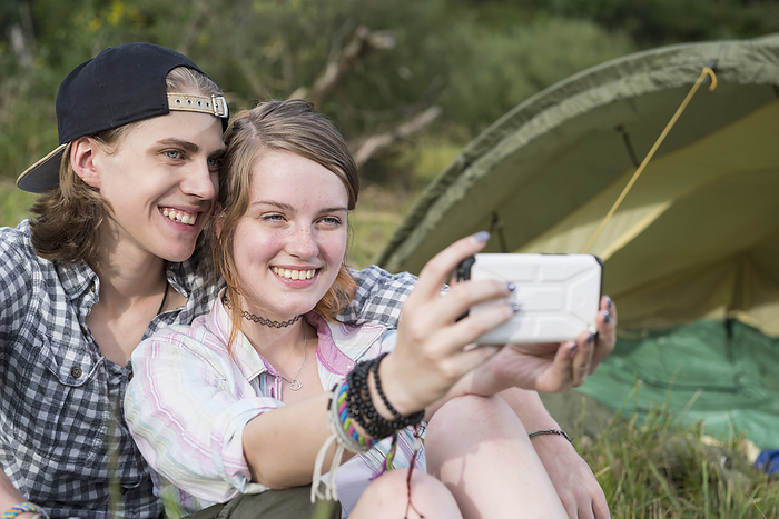 Young couple making a selfy with the smarthphone, tent, camping Young couple smiling and taking selfie with smart phone in front of camp tent, Bavaria, Germany