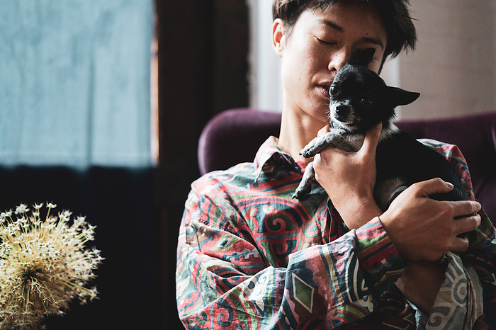 tender candid portrait of mixed-race person with tiny dog at home
