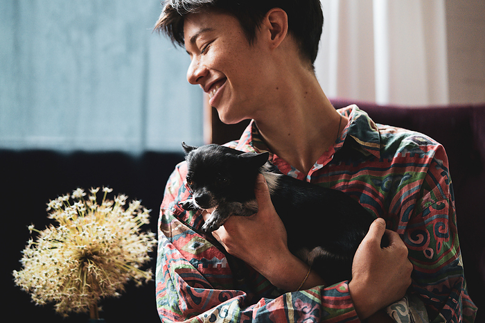 Happy portrait of mixed-race person holding tiny cute puppy dog