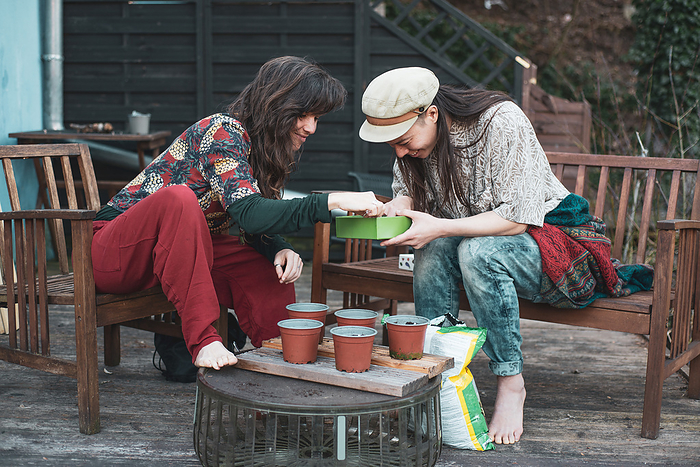 lesbian couple laugh as they garden spring pot plants