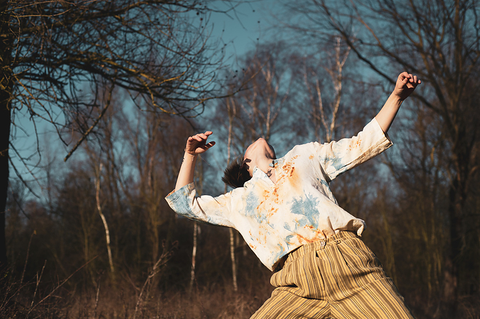 androgynous dancer dances freely with in nature with tree's and sun