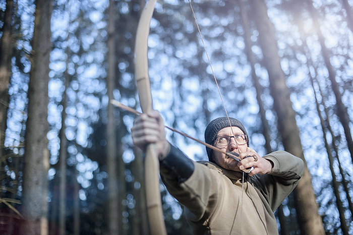 archer in forest Man shooting with bow and arrow in the forest, Bavaria, Germany