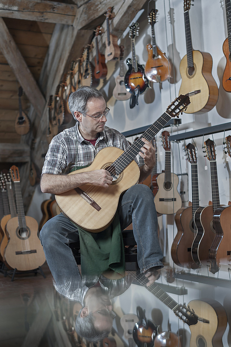 instrument maker studio,guitar maker playing his guitar in exhibition room, Guitar maker playing guitar in music store