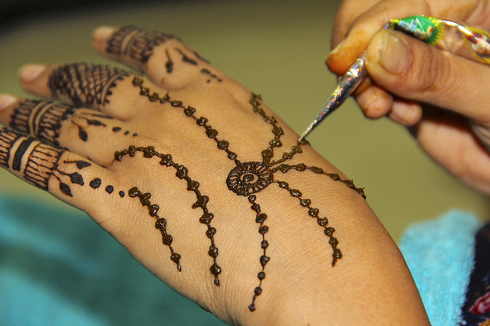 Woman drawing mehendi or tattoo on her own hand Woman drawing mehendi or tattoo on her own hand, by Zoonar RealityImages