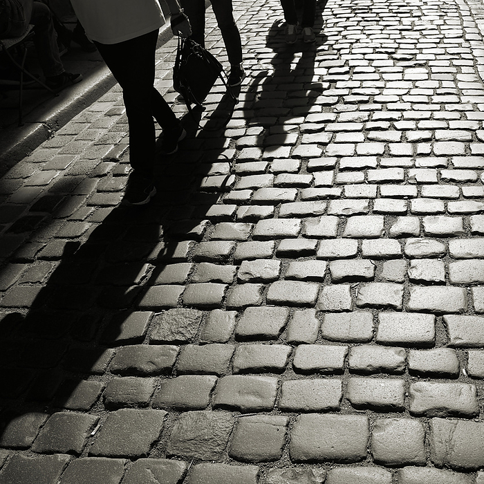 Shadow of oncoming people on cobblestones in backlight Shadow of oncoming people on cobblestones in backlight, by Zoonar Heiko Kueverl
