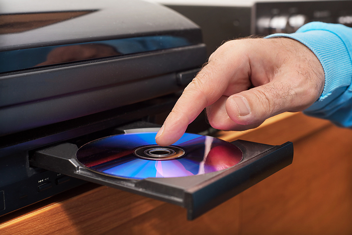 Hand holding DVD inserting to video player Hand holding DVD inserting to video player, by Zoonar DAVID HERRAEZ