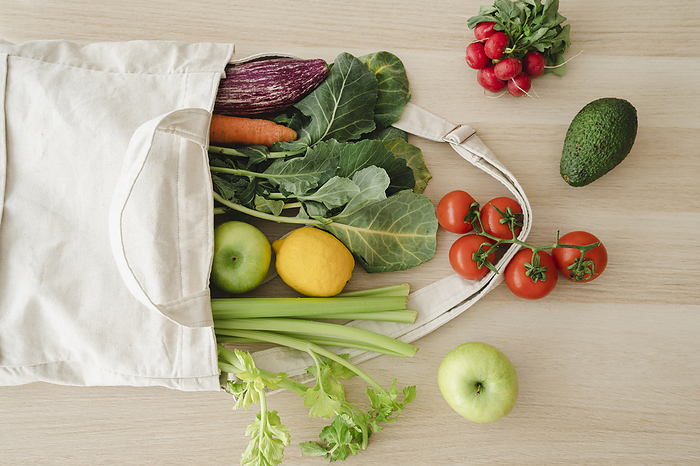 Fresh organic vegetables and fruits in reusable bag on table