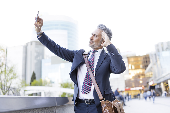 Business saluting and taking selfie through smart phone