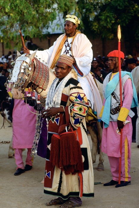 Nigeria A n honoured chief riding a decorated horse with his attendants at a Durbar in Maidugari, Nigeria