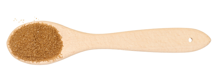 Wooden spoon with brown cane sugar on a white background, top view Wooden spoon with brown cane sugar on a white background, top view
