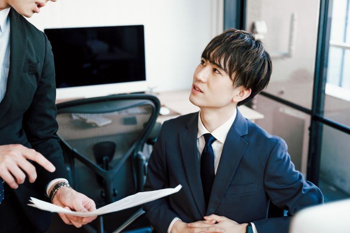 Two Japanese businessmen consulting with each other over documents in their office (People)