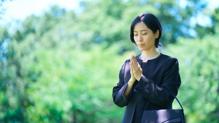 A Japanese woman in mourning attire with her palms together (People)