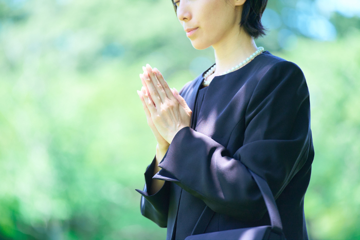 A Japanese woman in mourning attire with her palms together (People)