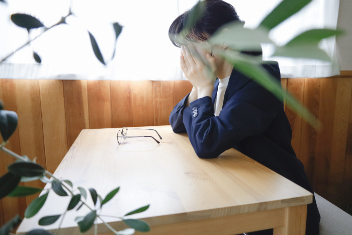 Woman in jacket sitting at desk with face covered