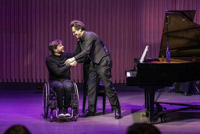 After a performance, an able-bodied concert pianist shakes hands with another pianist in a wheelchair who has a spinal cord injury; Edmonton, Alberta, Canada, by LJM Photo / Design Pics