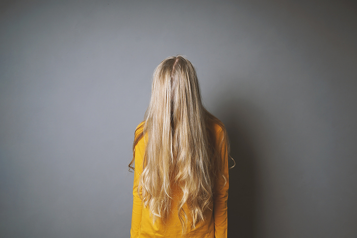depressed young woman hiding her face behind long blond hair depressed young woman hiding her face behind long blond hair, by Zoonar Axel Bueckert