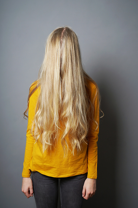 shy young woman with obscured face behind long blond hair shy young woman with obscured face behind long blond hair, by Zoonar Axel Bueckert