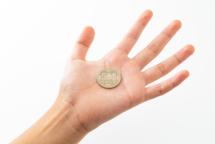 A child's hand holding a 500 yen coin