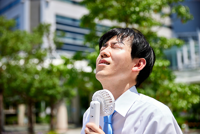 Japanese businessman using a portable fan