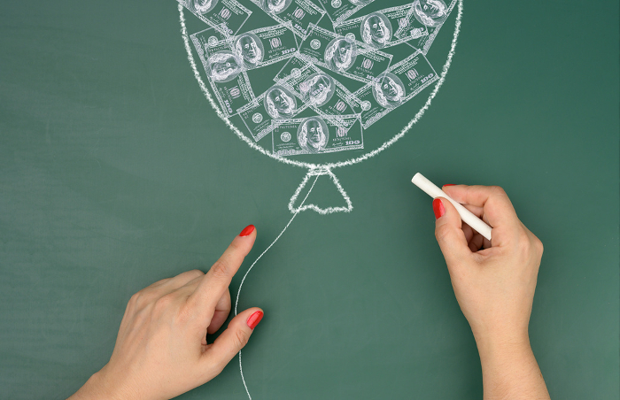 Chalk drawn balloon with drawn dollars and female hands, concept of inflation Chalk drawn balloon with drawn dollars and female hands, concept of inflation