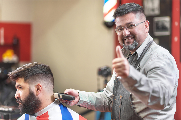 Portrait of a barber working while showing thumb up. Positive approval sign. Portrait of a barber working while showing thumb up. Positive approval sign.