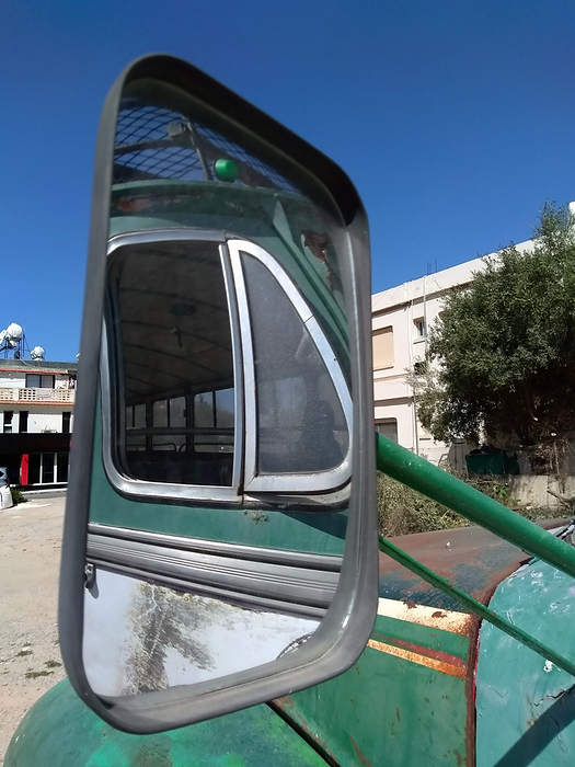 mirror of an old green bus with reflection of the side window in a square in a village in cyprus mirror of an old green bus with reflection of the side window in a square in a village in cyprus