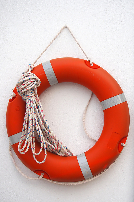 a round orange lifebelt with safety rope hanging on a white wall a round orange lifebelt with safety rope hanging on a white wall