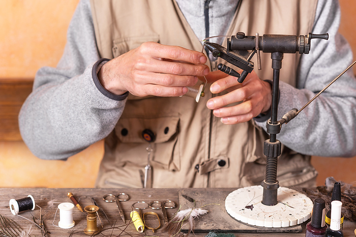 Man making trout flies. Fly tying equipment and material for fly fishing preparation. Man making trout flies. Fly tying equipment and material for fly fishing preparation.