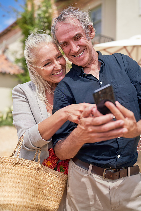 Happy senior couple using smart phone on sunny patio