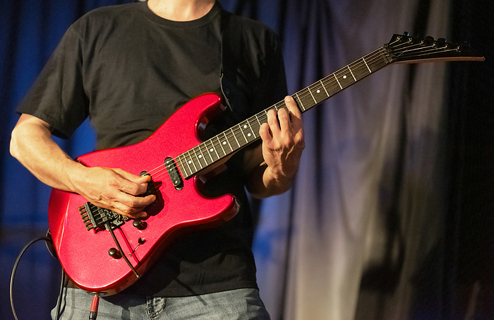 Musician playing red electric guitar on stage. Musician playing red electric guitar on stage.