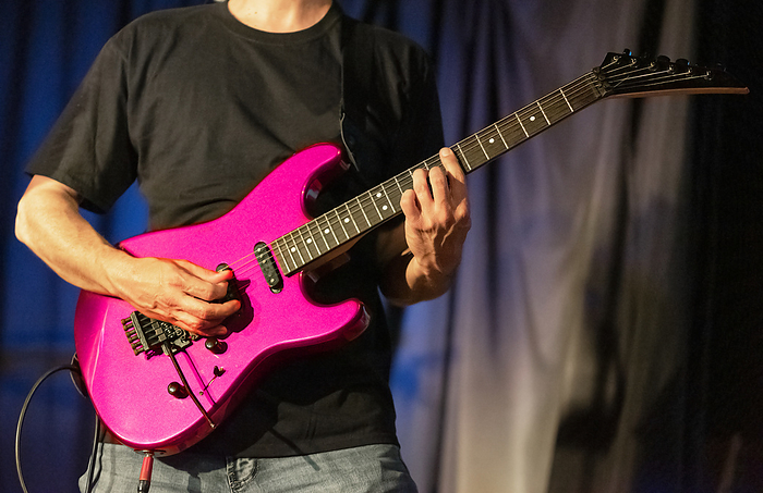 Musician playing pink electric guitar on stage. Musician playing pink electric guitar on stage.
