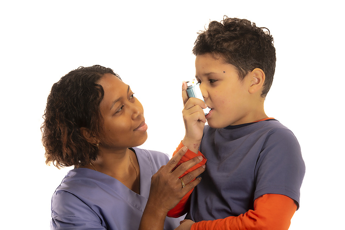 Boy using inhaler Healthcare professional assisting 7 year old boy using inhaler., by SAMUEL ASHFIELD SCIENCE PHOTO LIBRARY