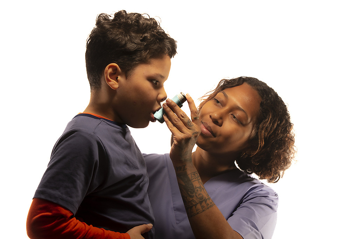 Boy using inhaler Healthcare professional assisting 7 year old boy using inhaler., by SAMUEL ASHFIELD SCIENCE PHOTO LIBRARY