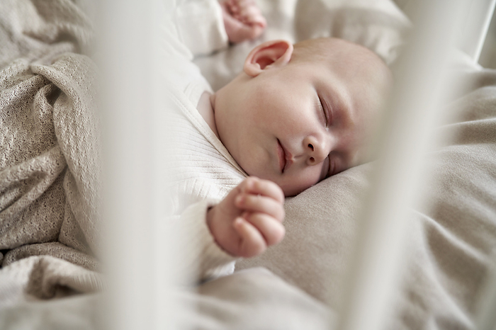 Newborn baby sleeping  in the crib Baby girl with eyes closed sleeping in crib