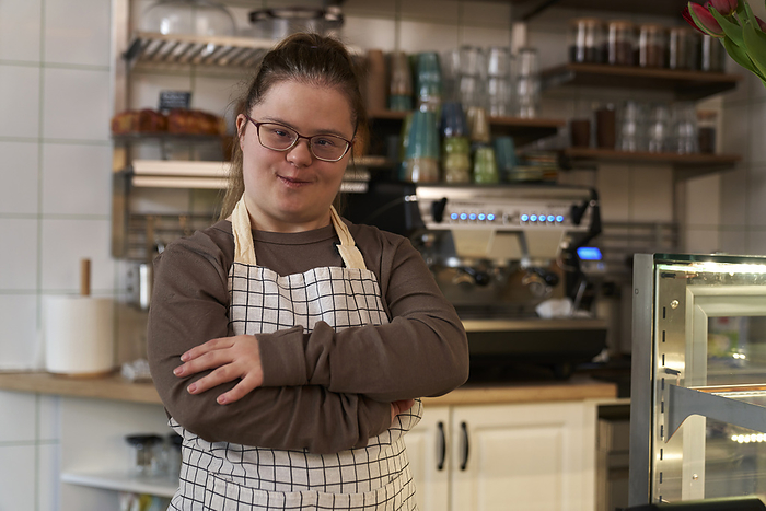 Portrait of down syndrome girl as a worker in the cafe Smiling cafe owner with down syndrome standing in coffee shop