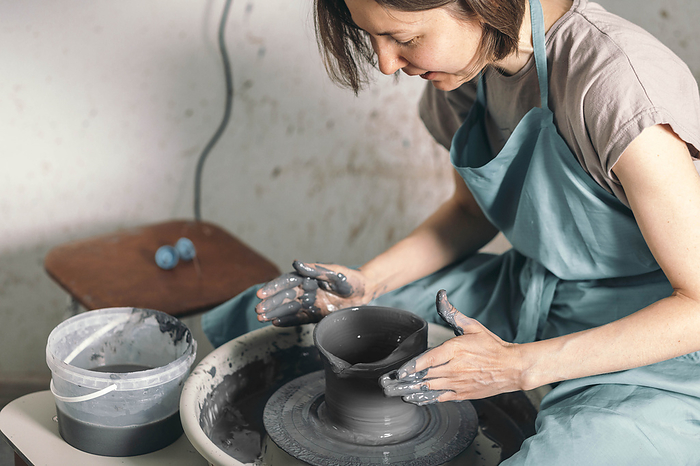 Potter wearing apron making ceramic pot at workshop