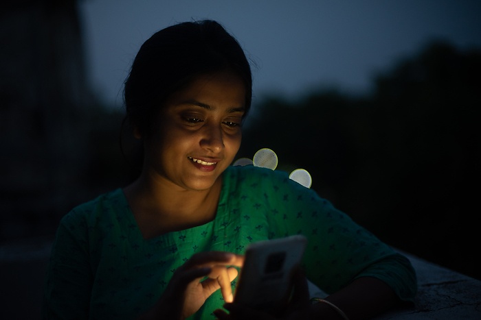 Young woman looking at mobile on rooftop in blue hour
