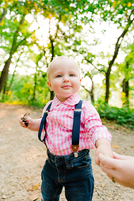 Straight on view of a toddler standing on a forest trail