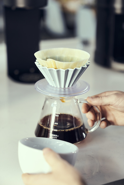 A coffee pour over is about to pour into a mug.