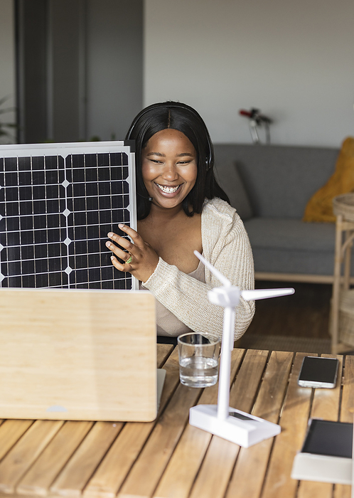 Smiling businesswoman with solar panel talking on video call over laptop