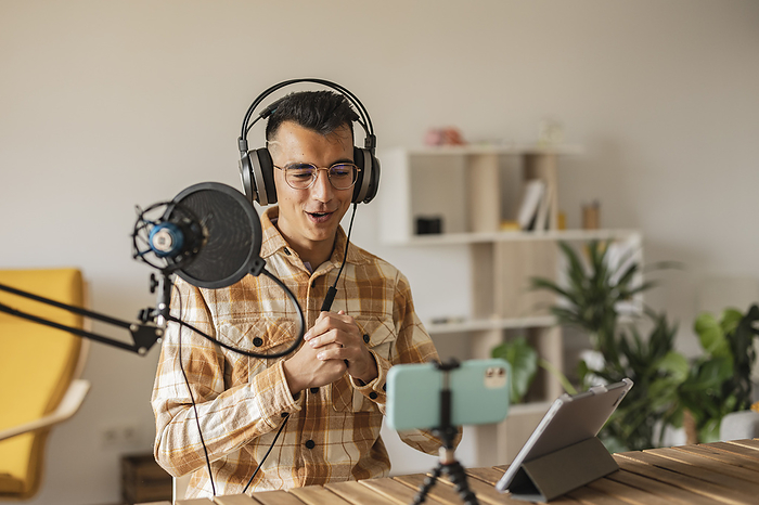 Man podcasting in front of smart phone and tablet PC at home