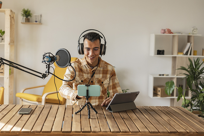 Man podcasting in front of smart phone and tablet PC at desk