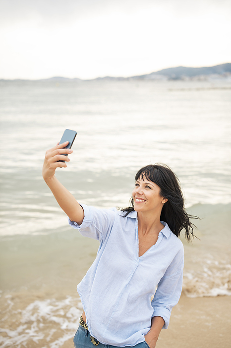 Smiling woman taking selfie through mobile phone at beach