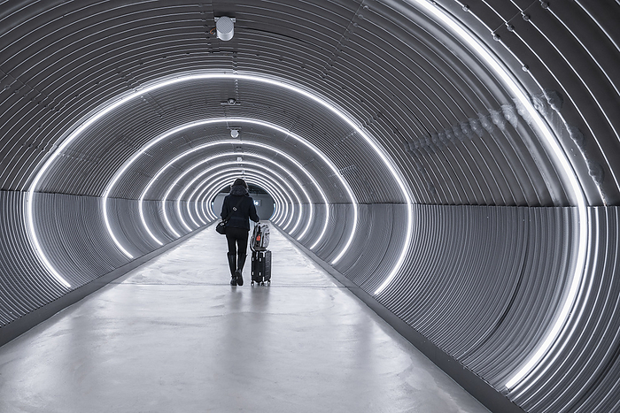Business traveller walking through lit up tunnel at Zurich airport