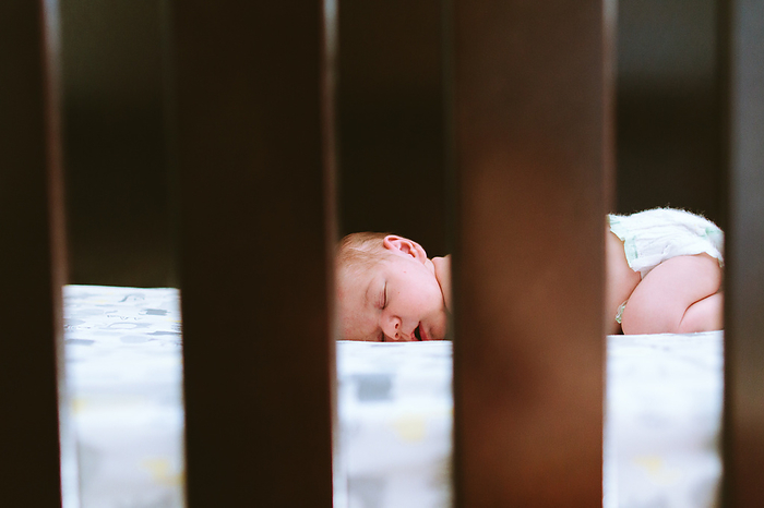 View through the crib slats of a baby boy sleeping