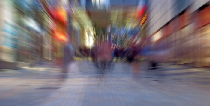 abstract zoom blur of a modern city street at night with people walking and bright illuminated buildings abstract zoom blur of a modern city street at night with people walking and bright illuminated buildings