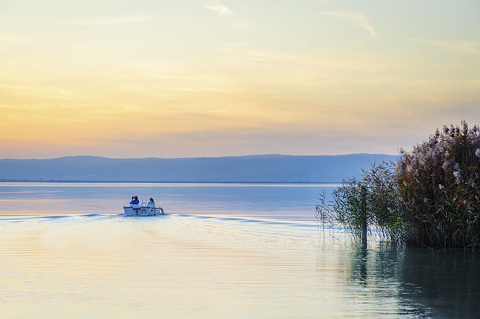 Couple in a small boat on a lake at sunset making selfie Couple in a small boat on a lake at sunset making selfie